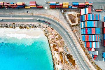 Shipping containers at Fremantle Port with white sandy beach and crystal clear blue sea