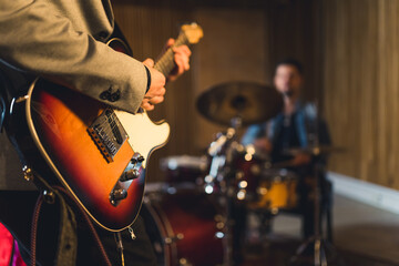 Close up of man playing electric guitar with a drummer. High quality photo