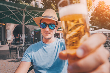 Tourist happy man wearing sunglasses and hat tasting and drinking traditional cologne koelsch beer in outdoor pub - obrazy, fototapety, plakaty