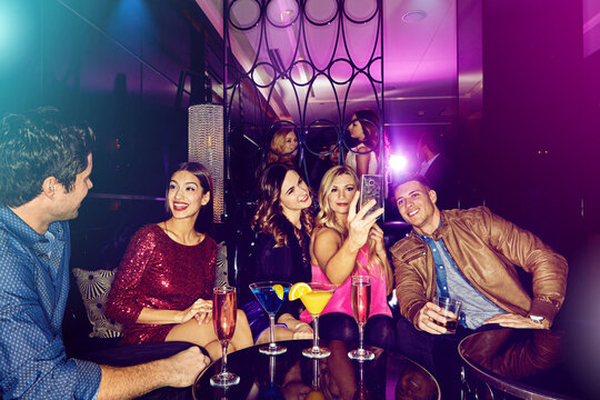 Friends group, nightclub selfie and phone for celebration, party and sitting on couch in night. Club cocktail, conversation and happy smartphone picture for social media, memory or new year in disco