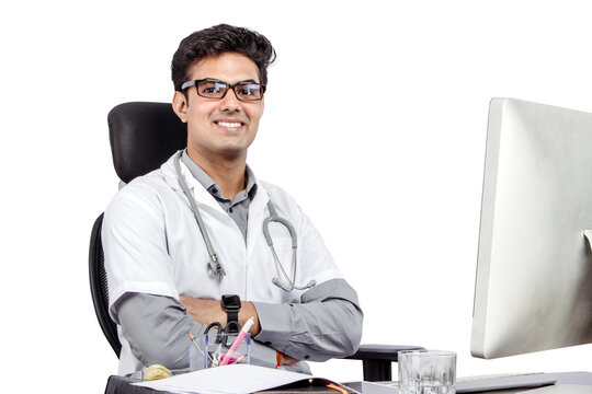 PNG of male male doctor working at office desk and smiling at camera, office interior on background