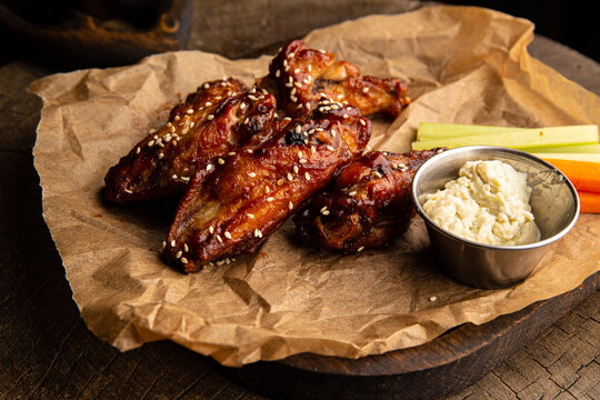 Chicken wings in teriyaki sauce with sticks of carrots, celery with sour cream sauce