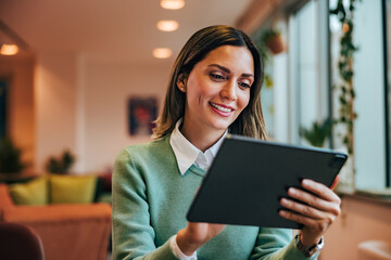 A businesswoman having a meeting with a colleague over the digital tablet, sitting at the home...