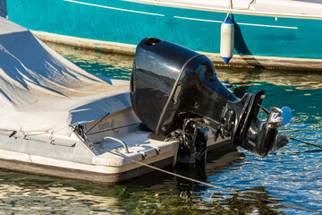 Close-up of a black outboard boat motor (engine and propeller). Small motor boat moored in the...
