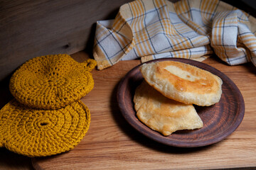 Clay plate of fried meat pies on wooden table.
