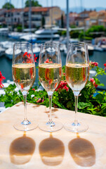 Drinking of French brut champagne sparkling wine in glasses in yacht harbour of Port Grimaud near Saint-Tropez, French Riviera vacation, France