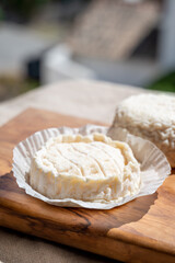French cheeses Rocamadour and Saint-Marcellin served on olive tree wooden plank with almonds