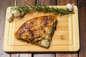 Tasty pie baked with meat with garlic and rosemary. On cutting board