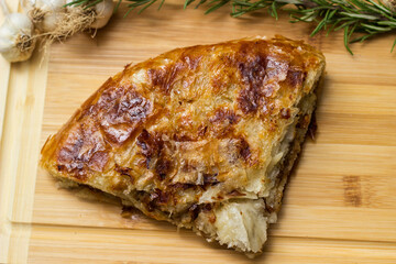 Tasty pie baked with meat with garlic and rosemary. On cutting board