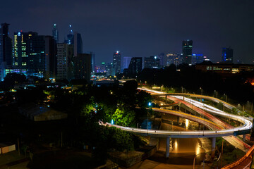 Fototapeta na wymiar Night photo of a glowing multi-level road junction with heavy traffic. Roads in the metropolis