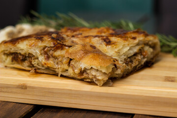 Tasty pie baked with meat with garlic and rosemary. On cutting board