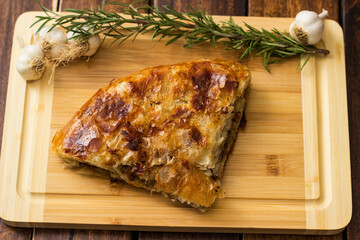 Tasty pie baked with meat with garlic and rosemary. On cutting board