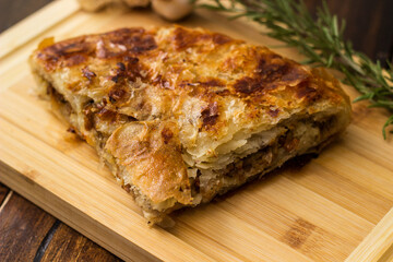 Tasty pie baked with meat with garlic and rosemary. On cutting board