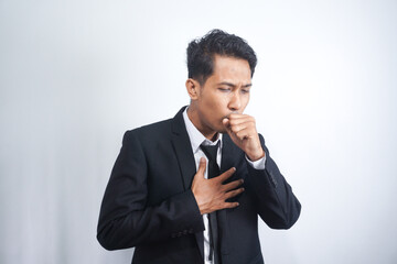 Man in suit coughing into his fist, isolated on a gray background.