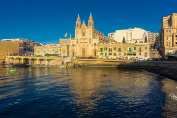Fototapeta na wymiar Sliema, Malta, 22 May 2022: The Cathedral right on the harbor of Sliema