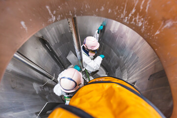 Inside male two worker into the inspection shiny tank stainless chemical  blower fresh air