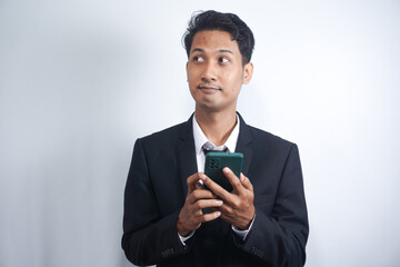Online Communication. Portrait Of Handsome Asian Businessman In Suit Holding Smartphone, Young Asian man Using Modern Device For Messaging Or Internet Browsing, Looking At Screen And Smiling