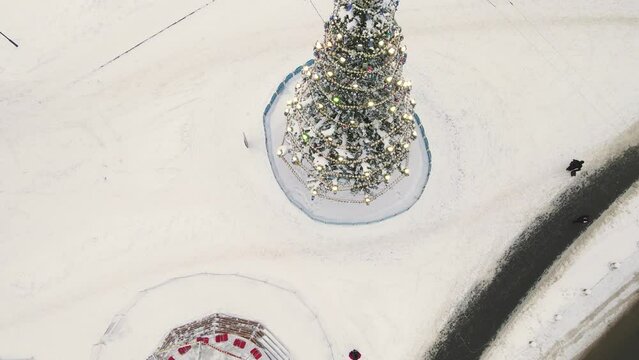 Beautifully decorated Christmas tree in the town square, aerial view. New Year's, green spruce fabulously decorated and covered with snow. City of Vladimir, Cathedral Square, Russia. UHD 4K.