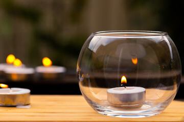 Obraz na płótnie Canvas An image showing decorative miniature candles, one inside a glass bowl and others outside on a timber tabletop, ideal as a relaxation theme or mood background.