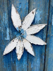 large vertical photo. blue vertical wooden boards. fence design. flower from white wooden boards. wooden wall decoration. remnants of antiquity. natural materials.