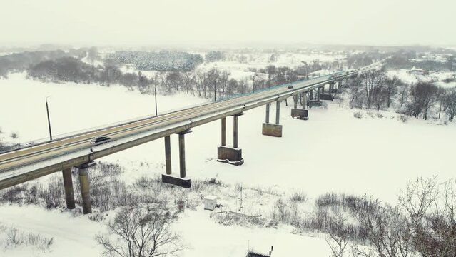 Bird's eye view of a road bridge over a frozen river in winter in the suburbs. Central Russia. Fabulous winter natural landscape, background, screensaver, footage, video. UHD 4K.