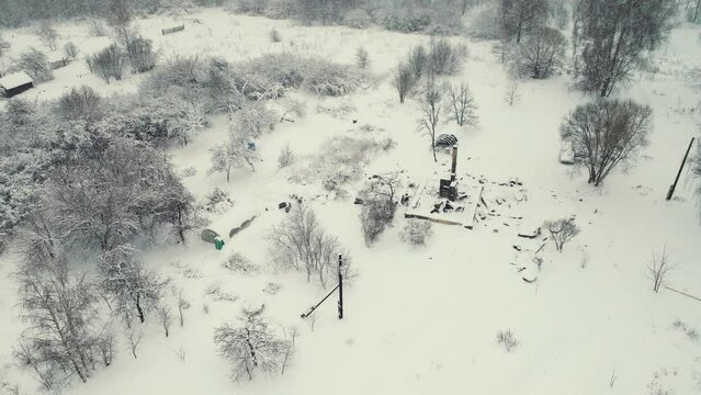 Aerial view of a destroyed stove in winter, the remains of a burnt house. War, a bombed-out house, a consequence of the bombing, rocket attacks. Snow-covered ruins abandoned by people. UHD 4K.