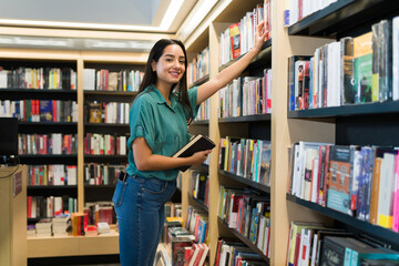 Portrait of a young woman shopping at the book shop - obrazy, fototapety, plakaty