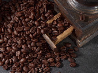Antique vintage retro bronze coffee mill on black wooden board with roasted coffee beans