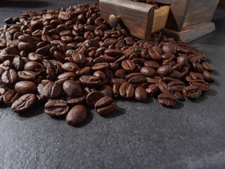 Antique vintage retro bronze coffee mill on black wooden board with roasted coffee beans