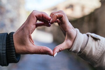 Close up shot of young couple joining hands to make the shape of a heart.