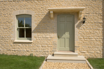 UK real estate. New house build, painted front door in stone wall.