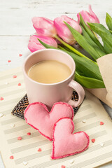 Romantic flat lay composition with a cup of coffee, soft felt hearts, and fresh tulips