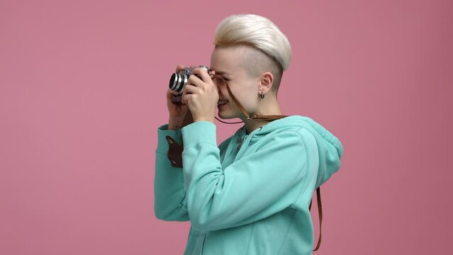 Close-up view of professional female photographer working indoors. Smiling, cheerful girl in her 30s taking photos in the studio. High quality 4k footage