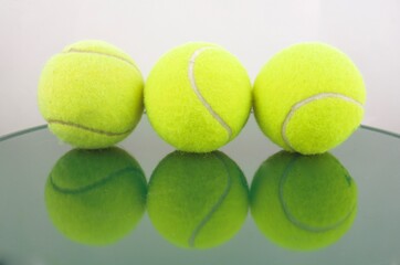 Three tennis balls reflected in green tones