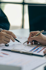 Naklejka premium Group of business people holding pen brainstorm financial analysis with financial graph document Calculator and computer to calculate budget and loan. Investment. Vertical image.