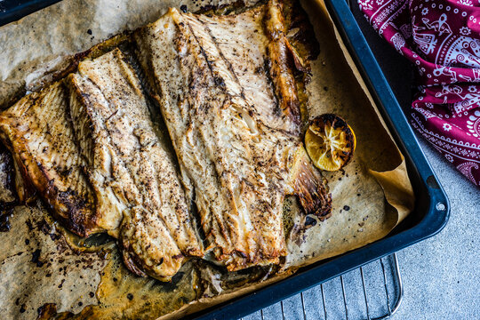 Close-up of roasted trout with lemon and herb on a baking tray