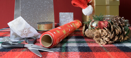 Preparing a Christmas present. banner format. Ribbon boxes, scissors, gift paper, etc. on a checkered table