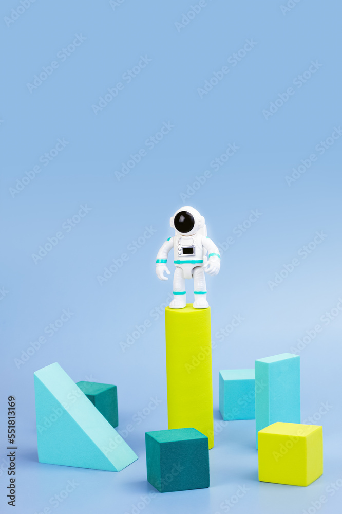 Wall mural plastic figurine of an astronaut in a spacesuit and geometric shapes on blue background. children's 