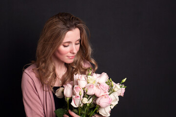 cute pretty girl holding a bouquet of roses in her hands on a dark background