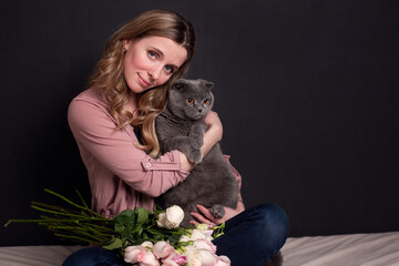 cute cute girl holding a gray cat in her arms on a dark background