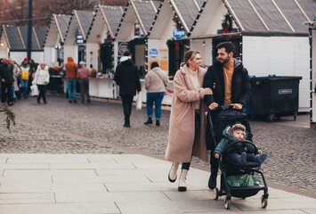 family on a walk with a baby in a stroller through the Christmas market