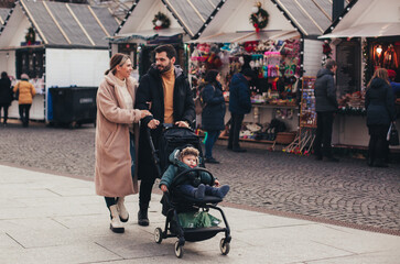 family on a walk with a baby in a stroller through the Christmas market