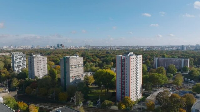 Forwards fly over tall residential buildings at large Tiergarten park. Aerial panoramic view of greenery in city. Berlin, Germany
