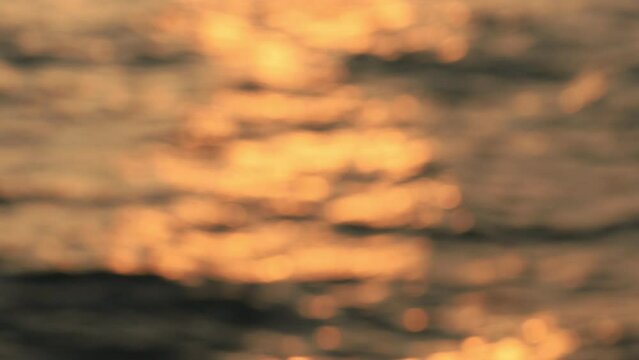 Blurred background of ocean wave moving with the golden sunlight at sunset 