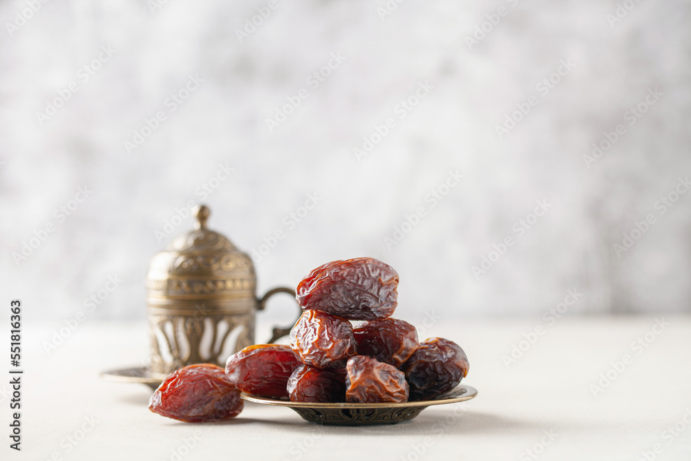 Wall mural Cup of coffee and dry dates on saucer ready to eat for iftar time. Islamic religion and ramadan concept.