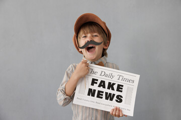 Newsboy shouting against grunge wall background. Boy selling fake news