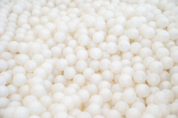 Background of many shiny white plastic balls in a ball house. It likes a many pearl  in the pool.