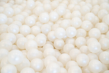 Background of many shiny white plastic balls in a ball house. It likes a many pearl  in the pool.
