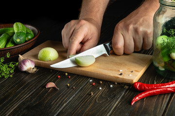 Chef cuts fresh onions for pickling with spices and cucumbers. Close-up of the cook hands while...