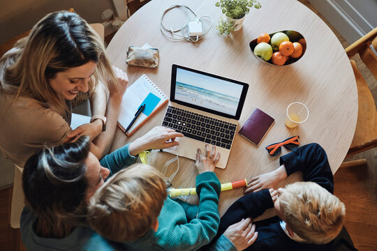 Directly above view of lesbian women planning vacation with sons on laptop at home
